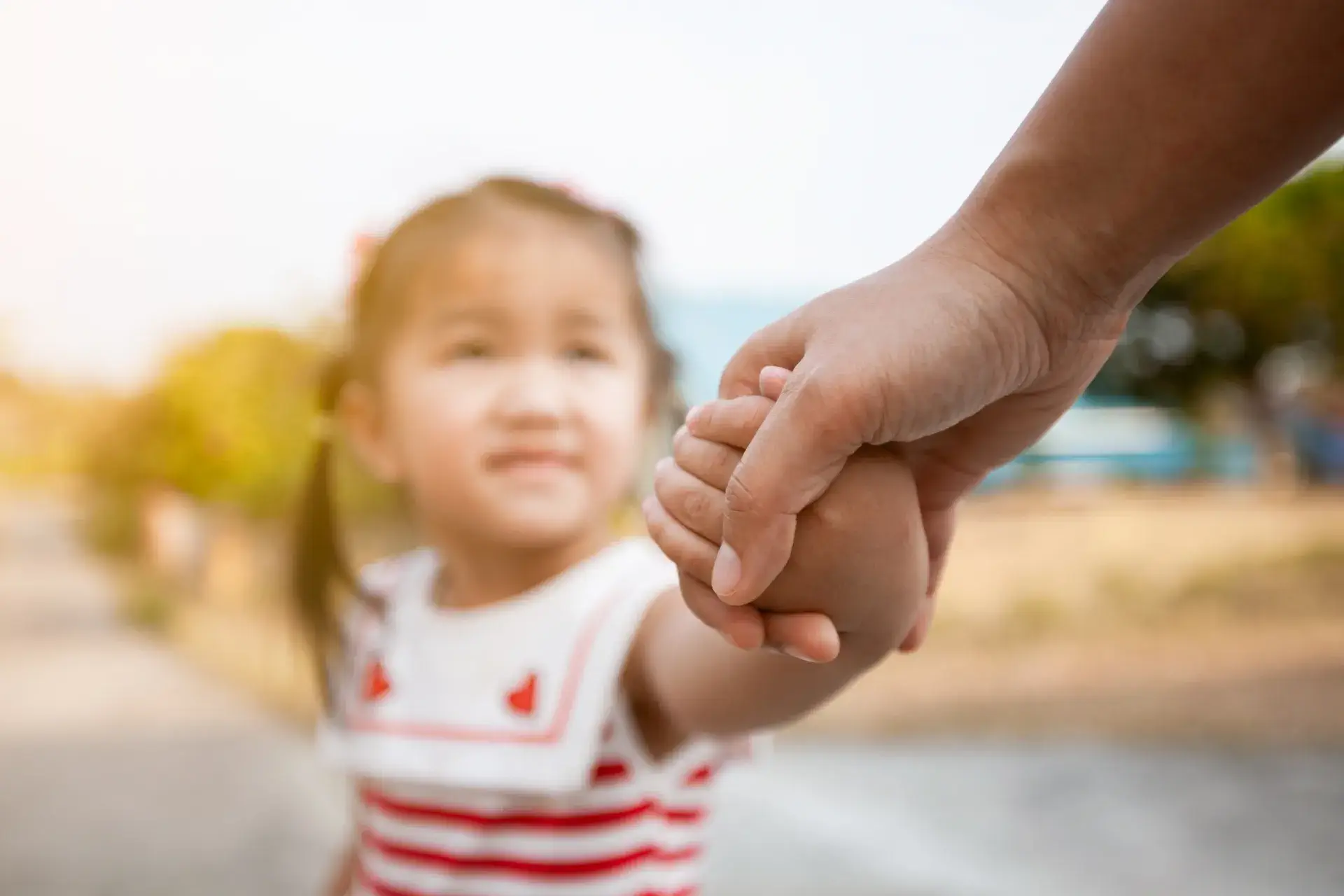 A child holding hands with a parent amidst child custody decisions in Singapore.